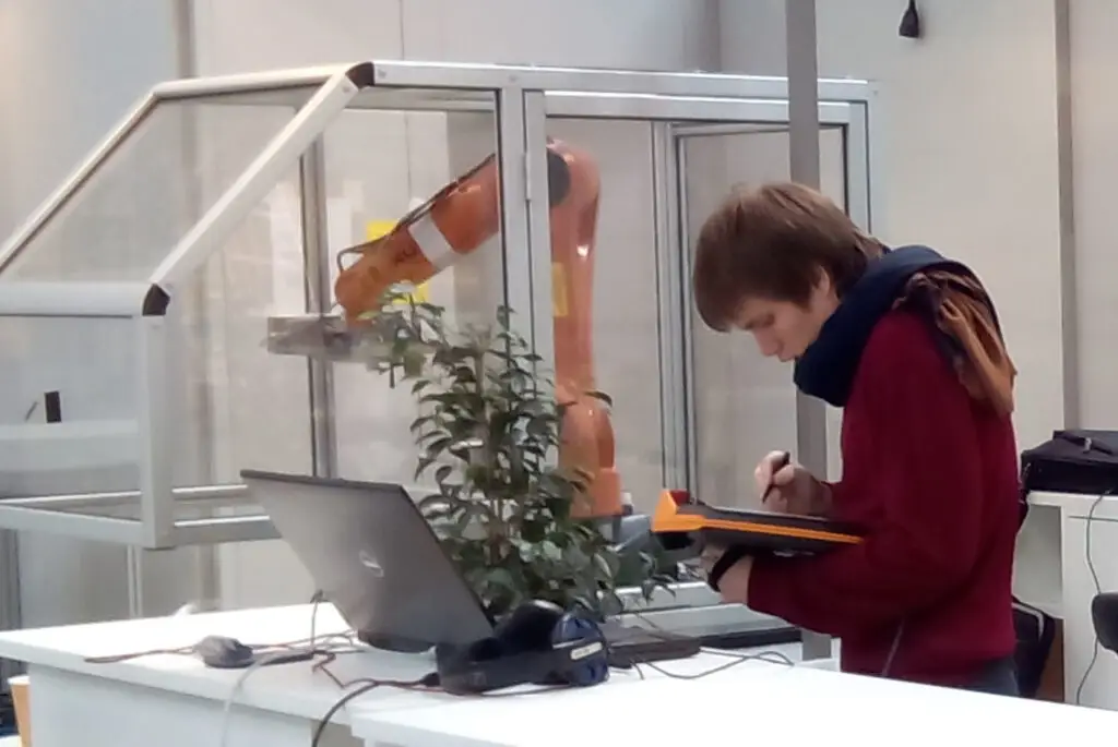 Photo de Boris Bocquet en train de programmer un robot polyarticulé industriel via le teach pendant.